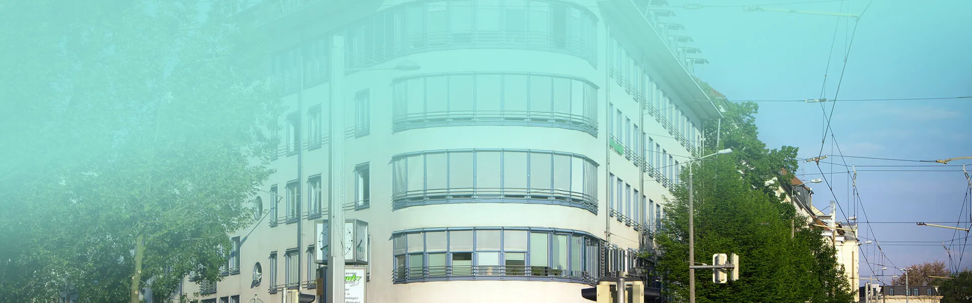 Modernes weißes Gebäude mit geschwungener Glasfassade und großen Fensterfronten in städtischer Umgebung