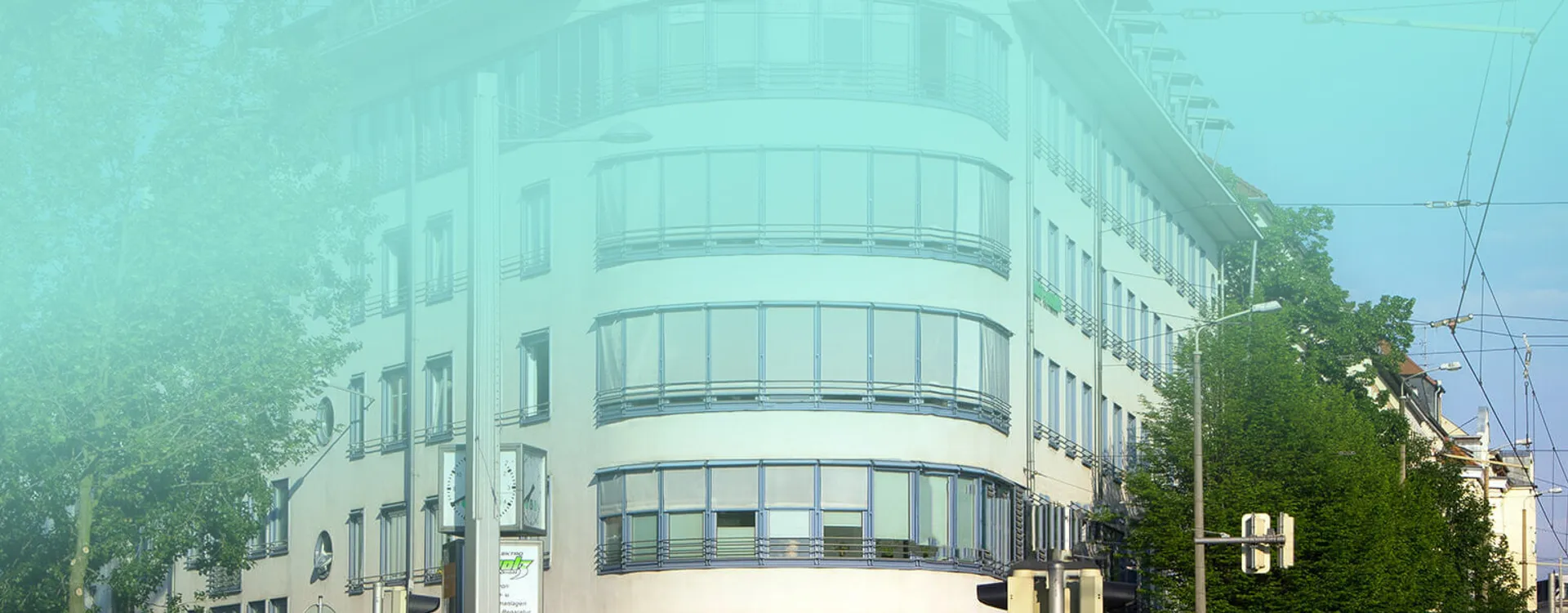 Modernes weißes Gebäude mit geschwungener Glasfassade und großen Fensterfronten in städtischer Umgebung