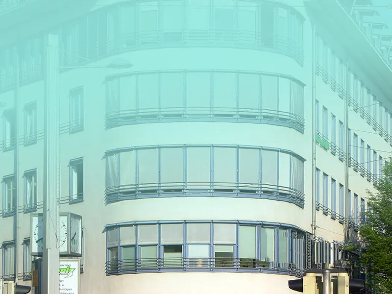 Modernes weißes Gebäude mit geschwungener Glasfassade und großen Fensterfronten in städtischer Umgebung